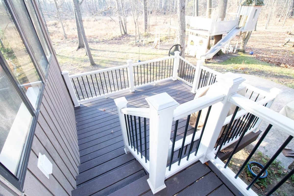 composite deck with white railing built with four seasons room addition by Odd Fellows Contracting in Haslett MI