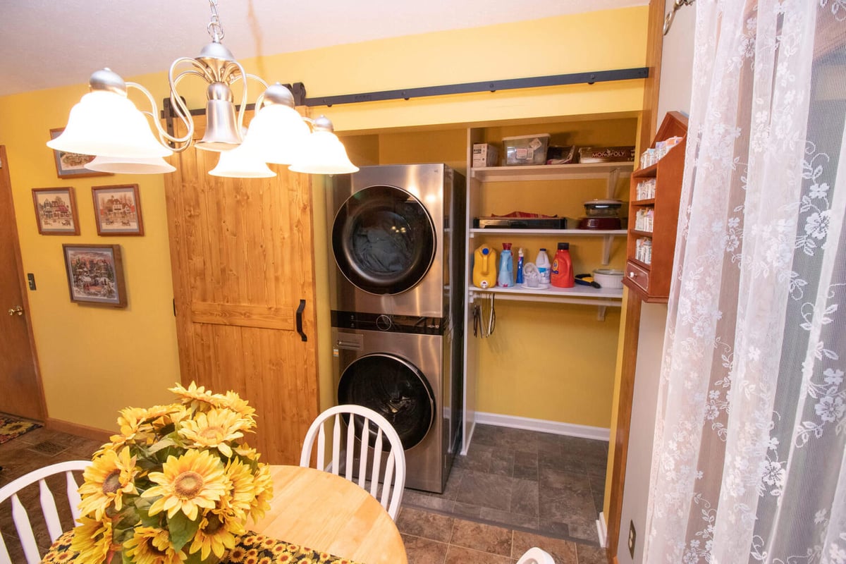 Laundry storage area with shelving and stacked appliances in garage addition by Odd Fellows Contracting in Williamston, MI