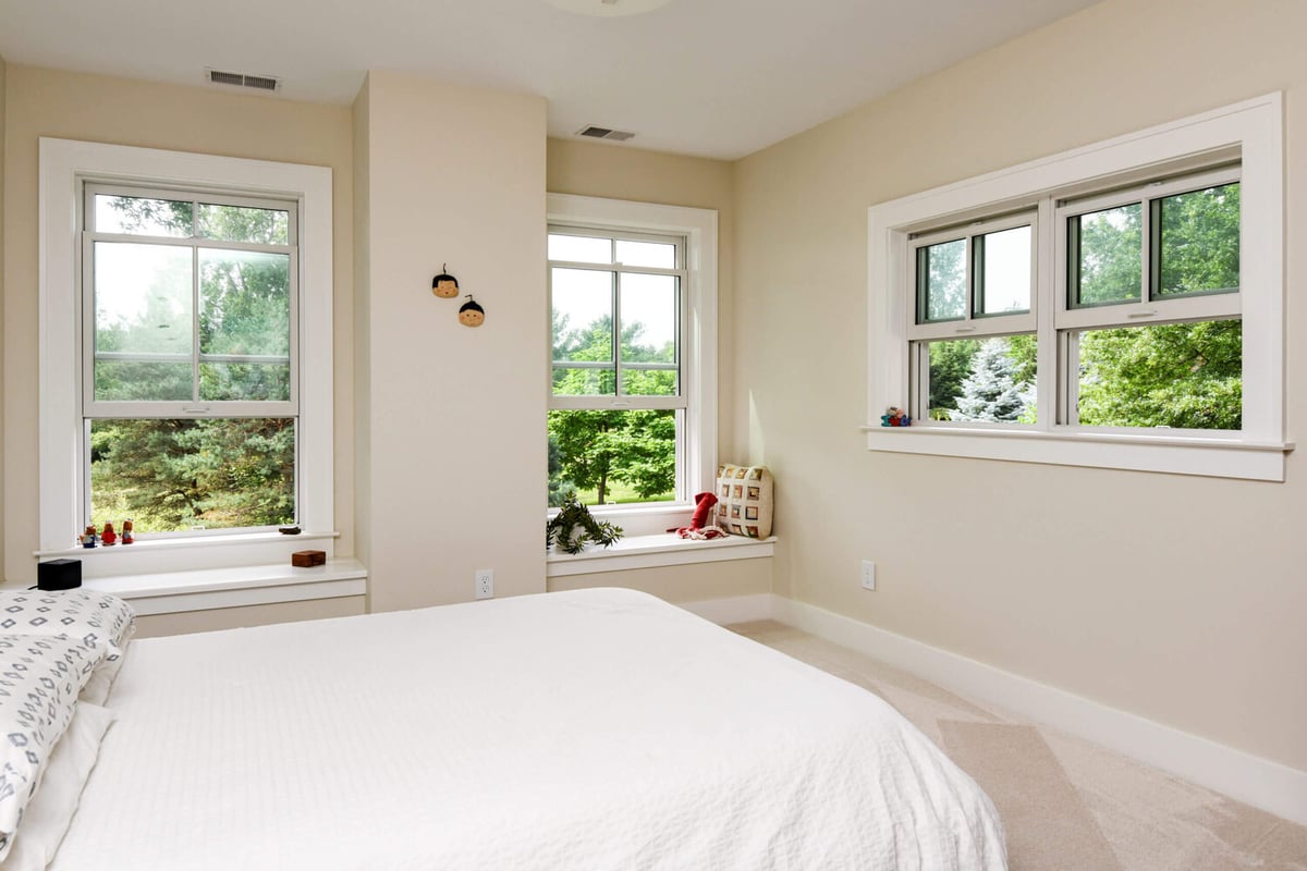 Bedroom from home addition project by Odd Fellows Contracting in Mason, MI featuring multiple windows and neutral finishes