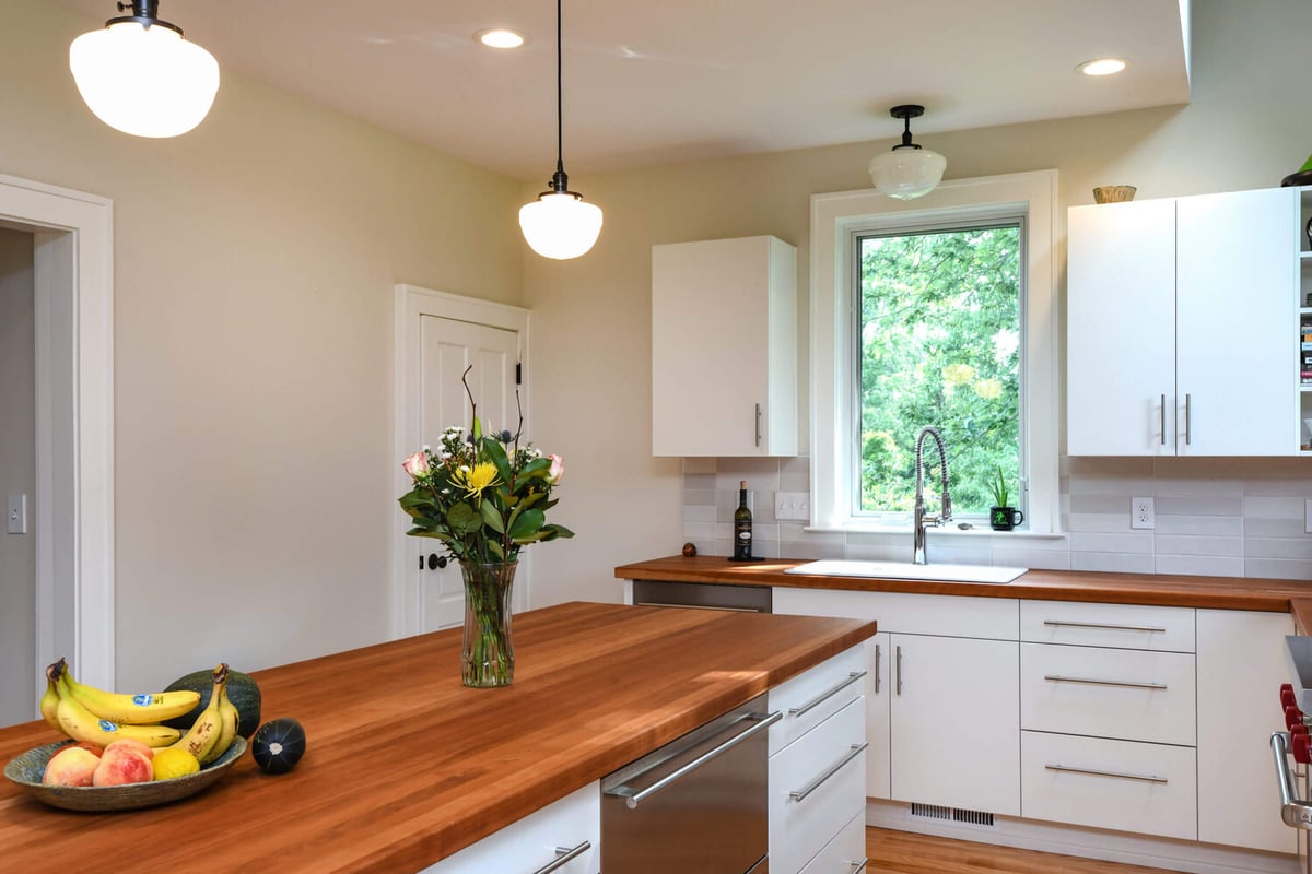 Kitchen island and sink area from home addition completed by Odd Fellows Contracting in Mason, MI with wood countertops and white cabinetry