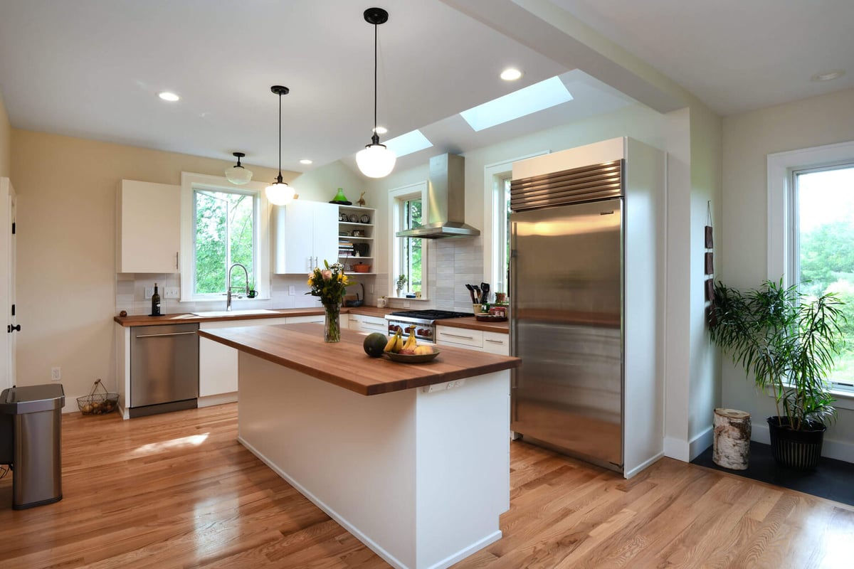 Modern kitchen addition with white cabinets, butcher block island, and skylights by Odd Fellows Contracting in Mason, M