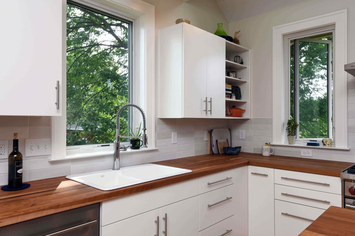 Natural light kitchen workspace with corner sink and cabinetry in home addition by Odd Fellows Contracting in Mason, MI
