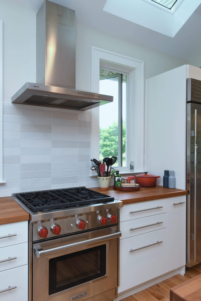 Stainless steel range and vent hood in kitchen addition completed by Odd Fellows Contracting in Mason, MI