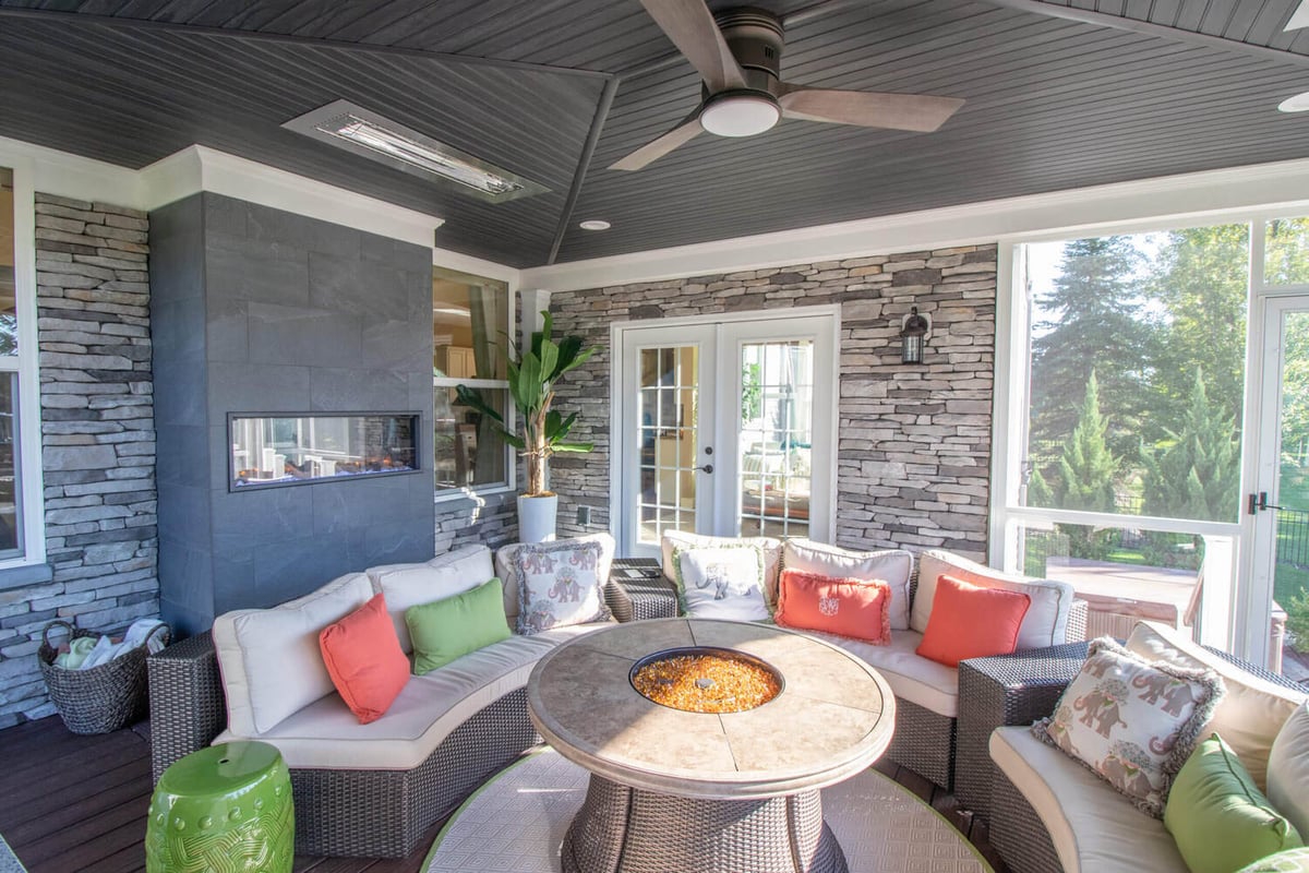 three season room with stone fireplace and lounge area by Odd Fellows Contracting Okemos MI