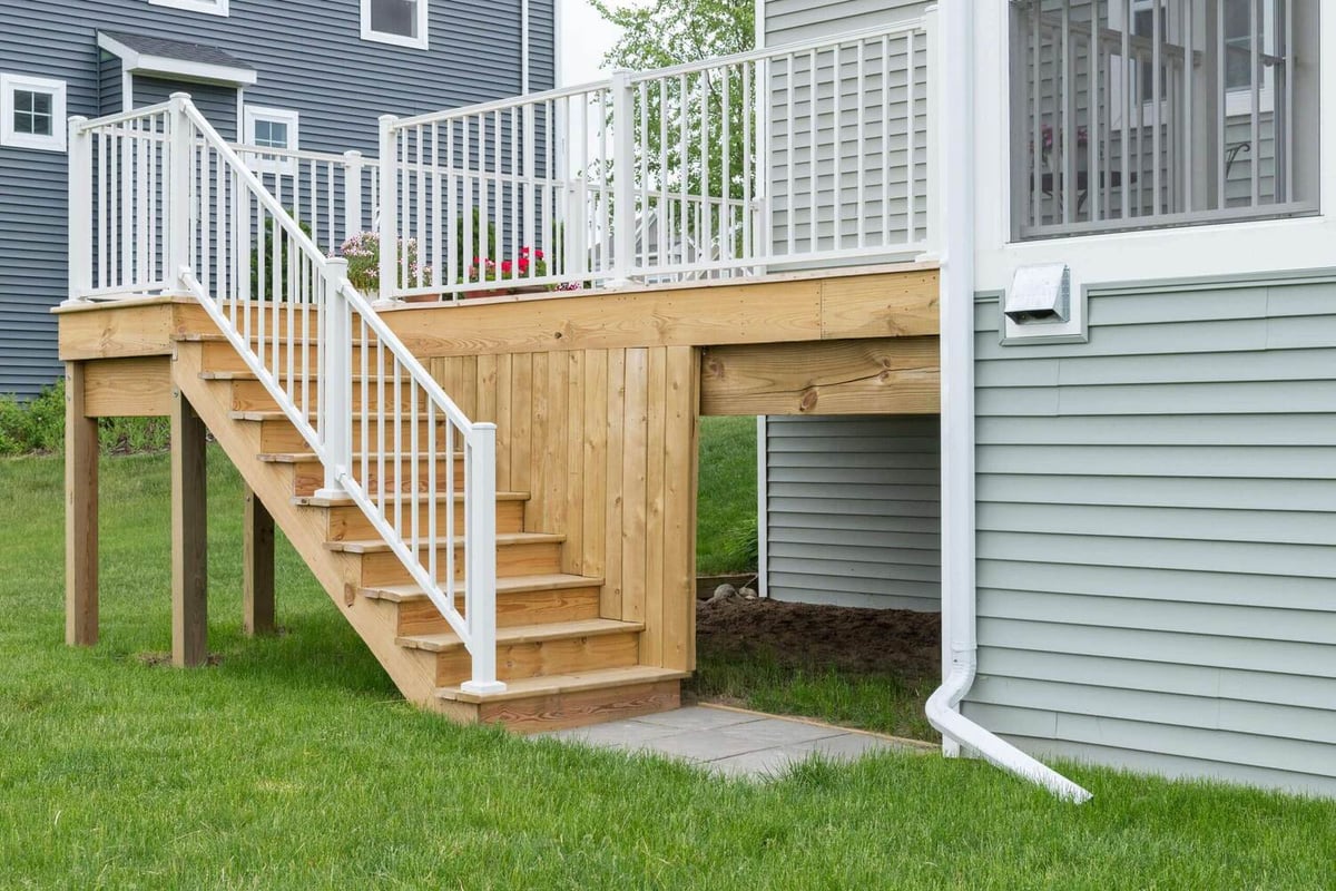 deck stairs with white railing leading to backyard by Odd Fellows Contracting in Lansing MI
