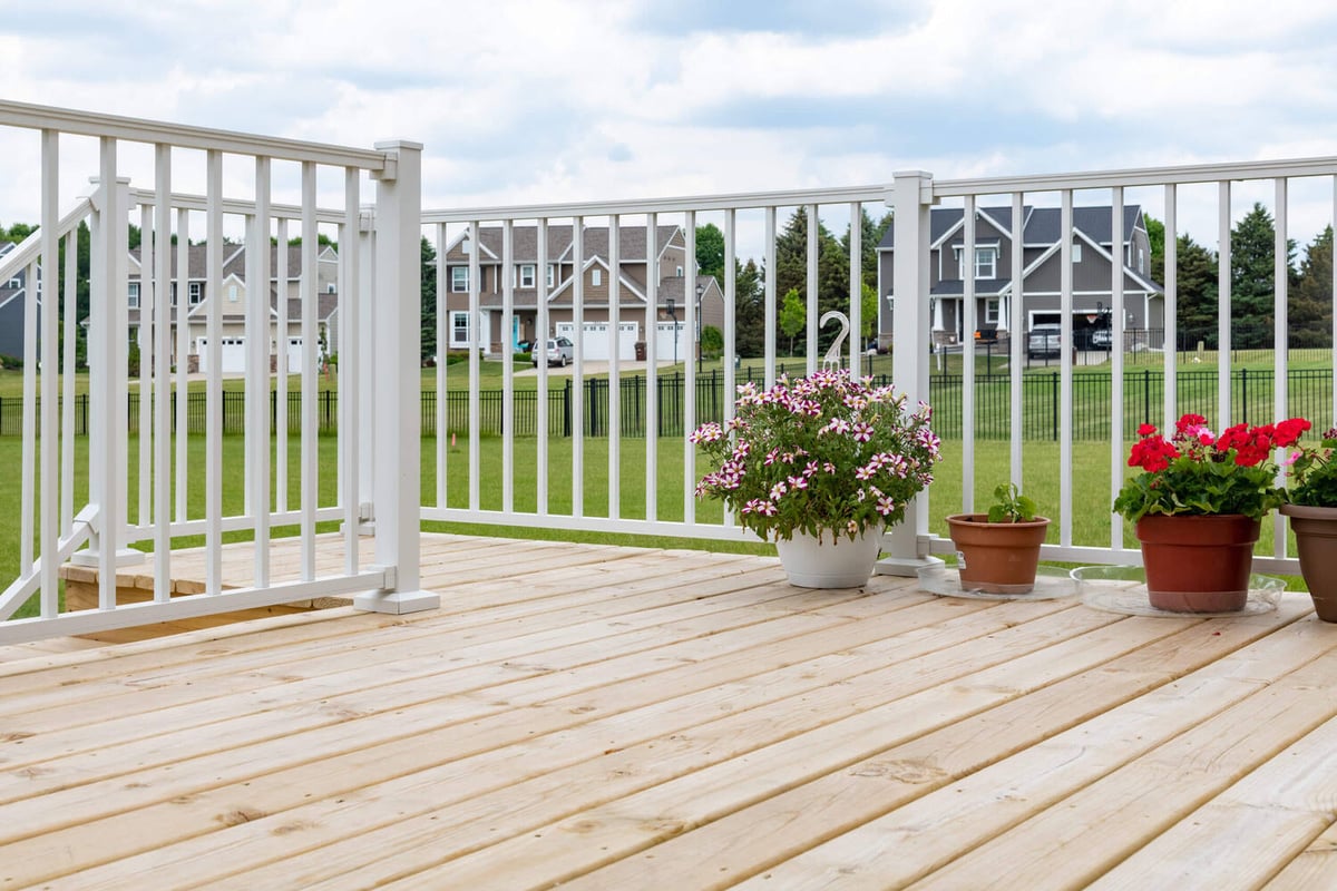 elevated wood deck with white railing and neighborhood view by Odd Fellows Contracting in Lansing MI