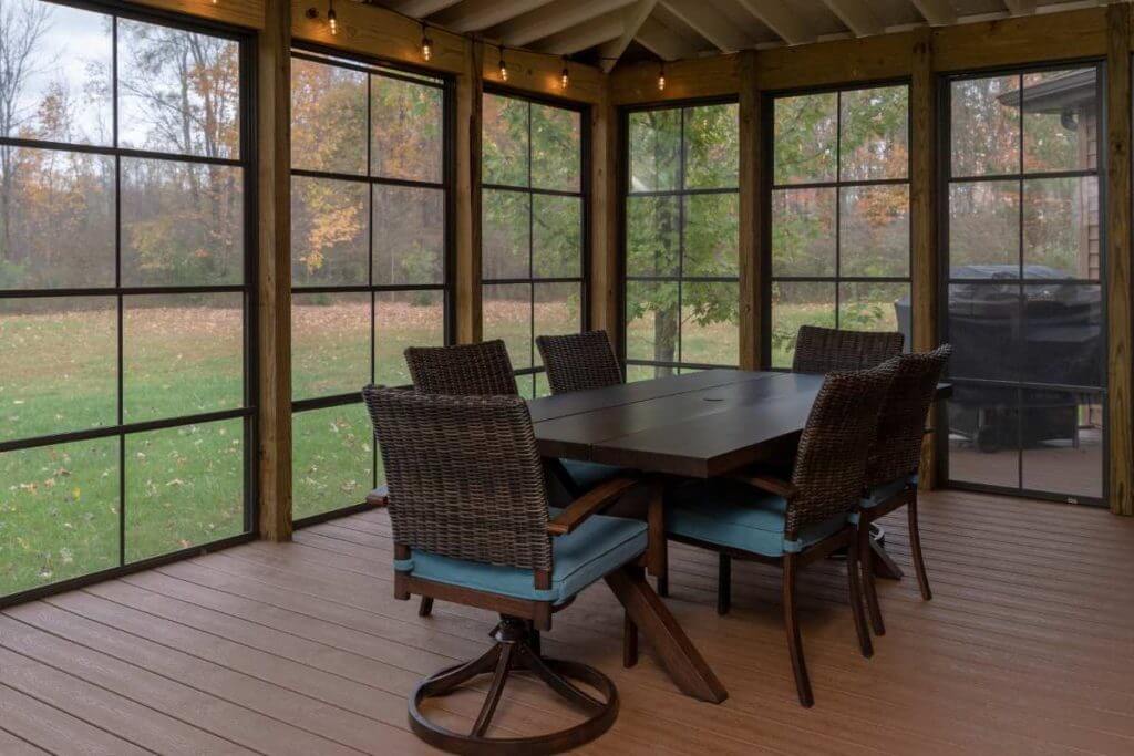interior three seasons room with dining table and screened windows by Odd Fellows Contracting in Grand Ledge MI