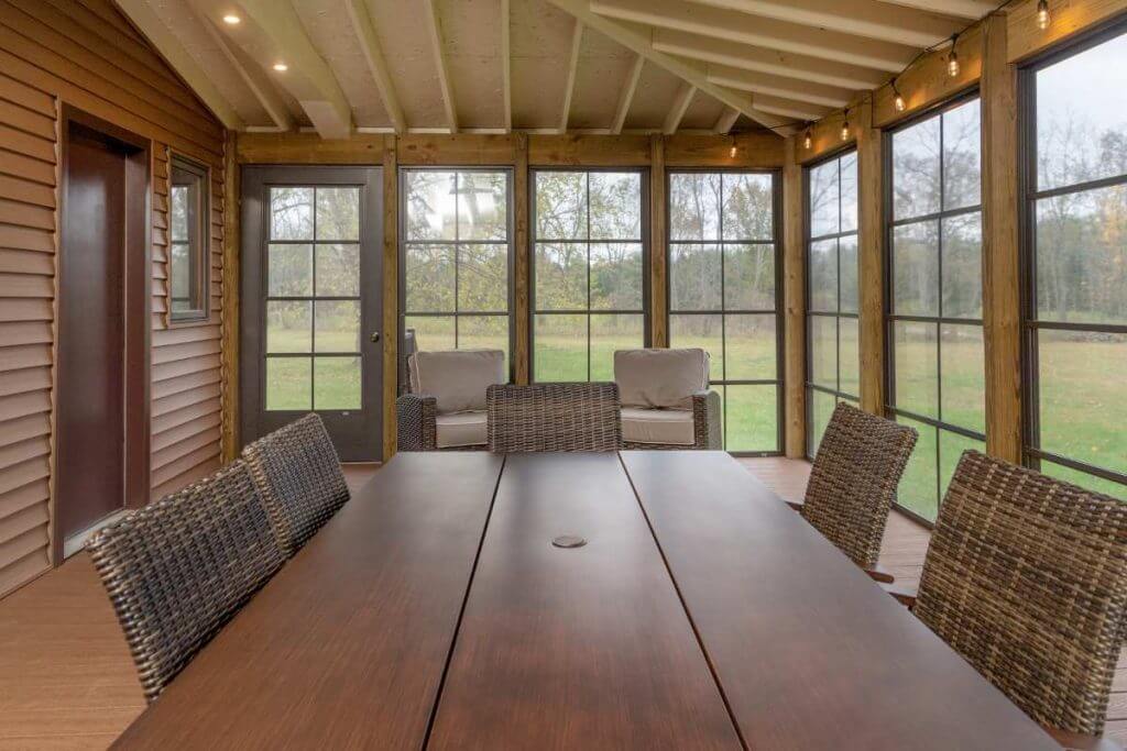 three seasons room interior with wicker chairs and screened windows by Odd Fellows Contracting in Grand Ledge MI