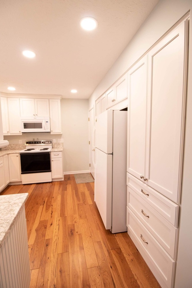 updated kitchen featuring white cabinets and modern lighting by Odd Fellows Contracting in Onondaga, MI