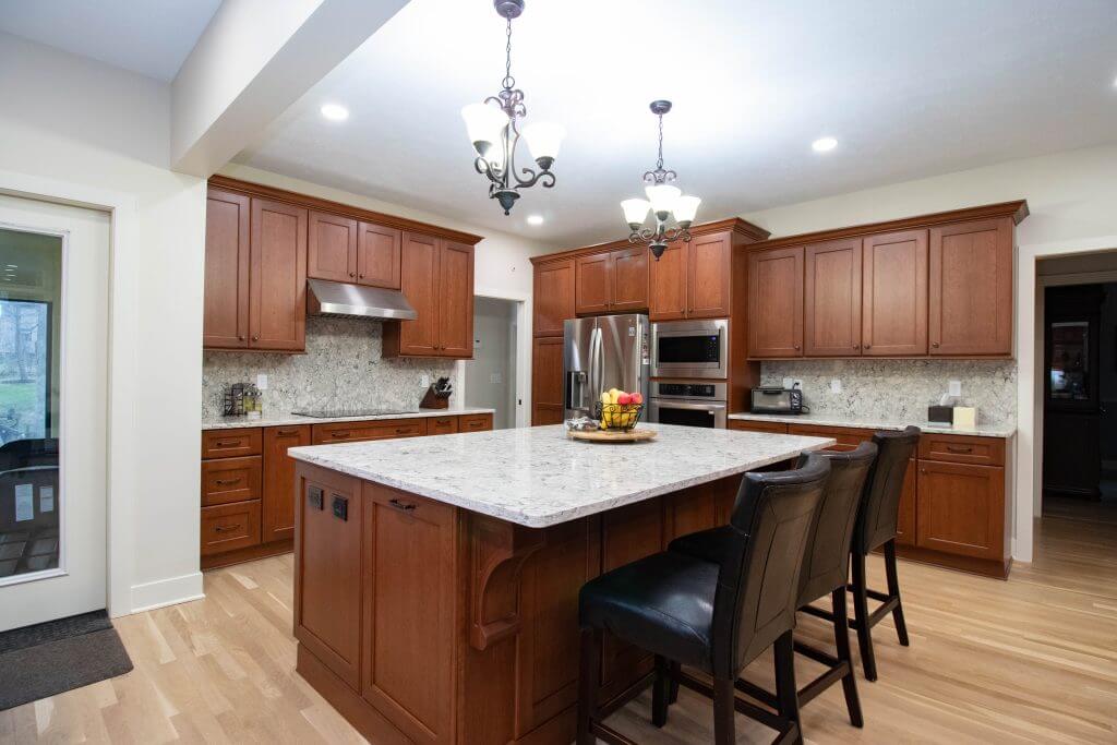 updated kitchen with quartz island and modern lighting by Odd Fellows Contracting in Okemos, MI