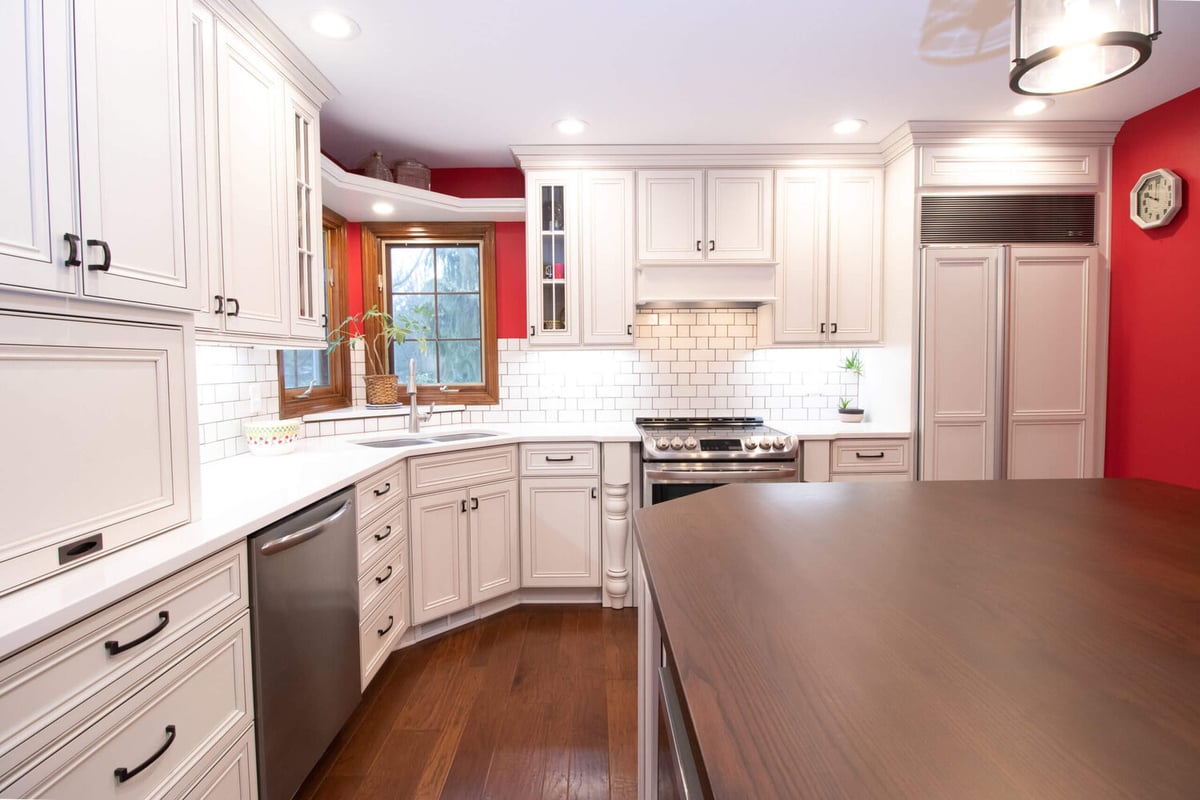 bright remodeled kitchen with white cabinetry, island workspace, and subway tile backsplash by Odd Fellows Contracting in Okemos, MI