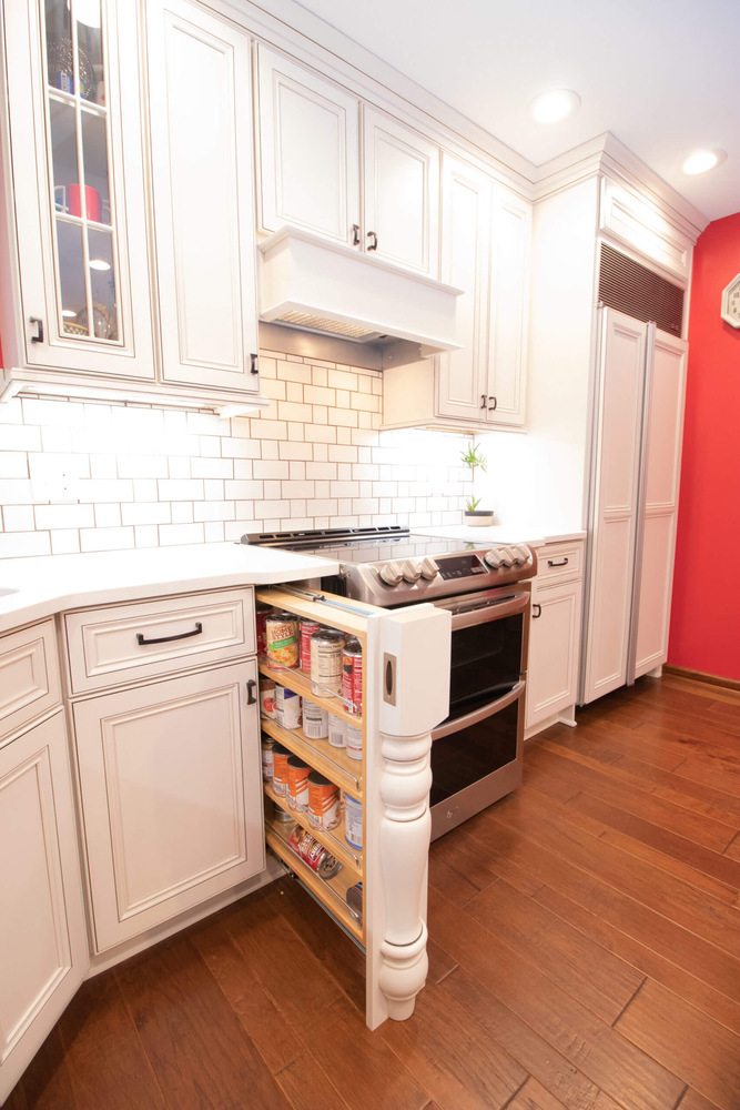 custom kitchen storage pull out pantry beside stainless steel range by Odd Fellows Contracting in Okemos, MI