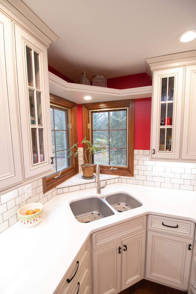 remodeled kitchen corner sink with white cabinets and subway tile backsplash by Odd Fellows Contracting in Okemos, MI