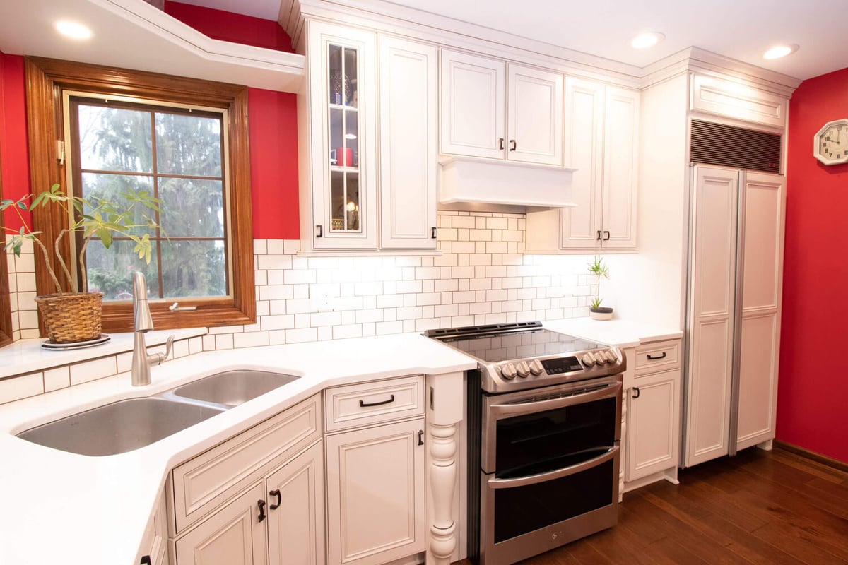 updated kitchen sink area with white cabinets and tile backsplash by Odd Fellows Contracting in Okemos, MI