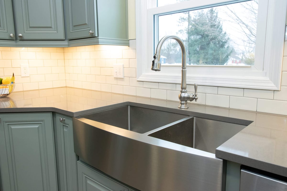 updated kitchen sink area with farmhouse sink and custom cabinets by Odd Fellows Contracting in Williamston, MI