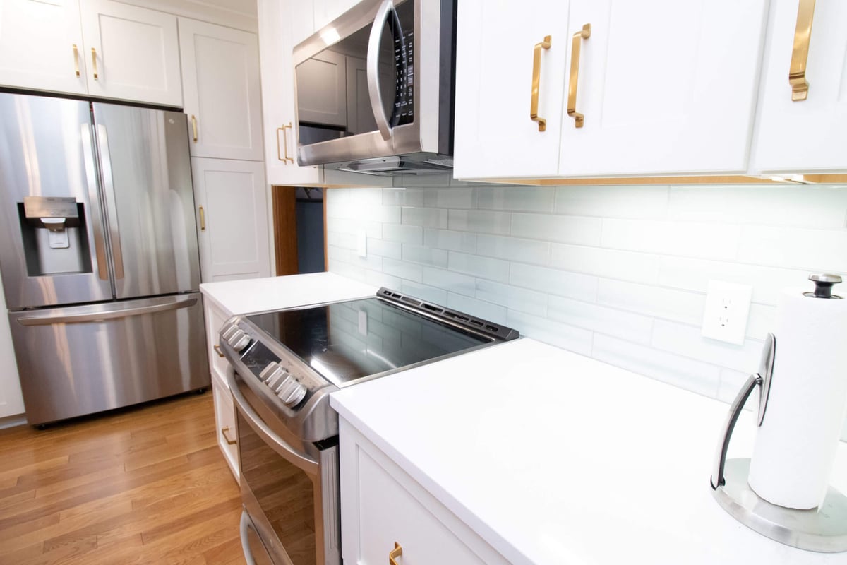 kitchen remodel showing stainless steel refrigerator surrounded by custom white cabinetry by Odd Fellows Contracting in Okemos, MI