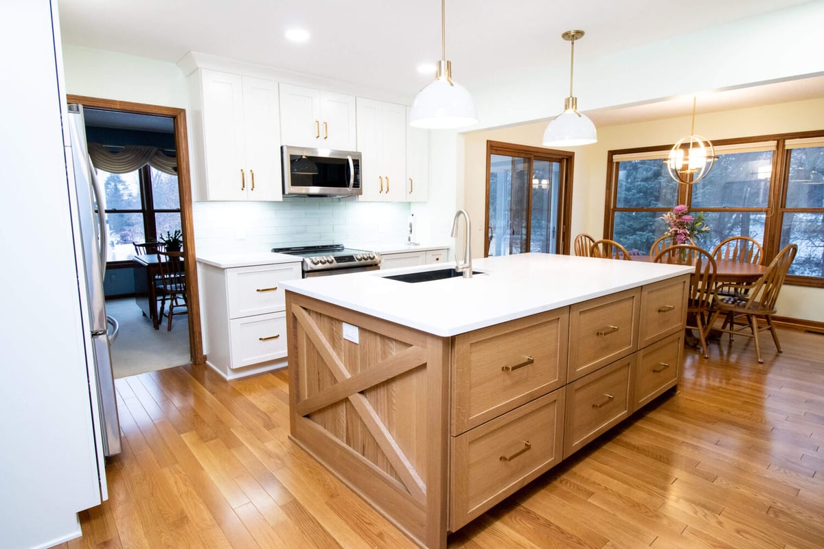 remodeled kitchen with large wood island, white cabinets, and quartz countertops by Odd Fellows Contracting in Okemos, MI