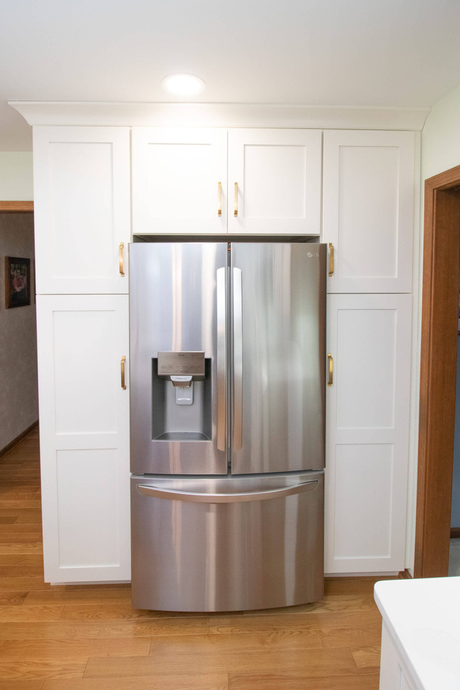 updated kitchen storage with built in refrigerator cabinet surround by Odd Fellows Contracting in Okemos, MI