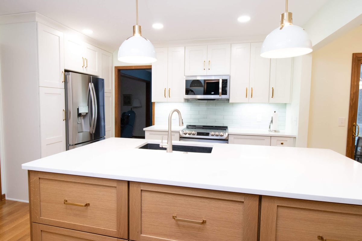 updated kitchen with custom island, white cabinets, and stainless steel appliances by Odd Fellows Contracting in Okemos, MI