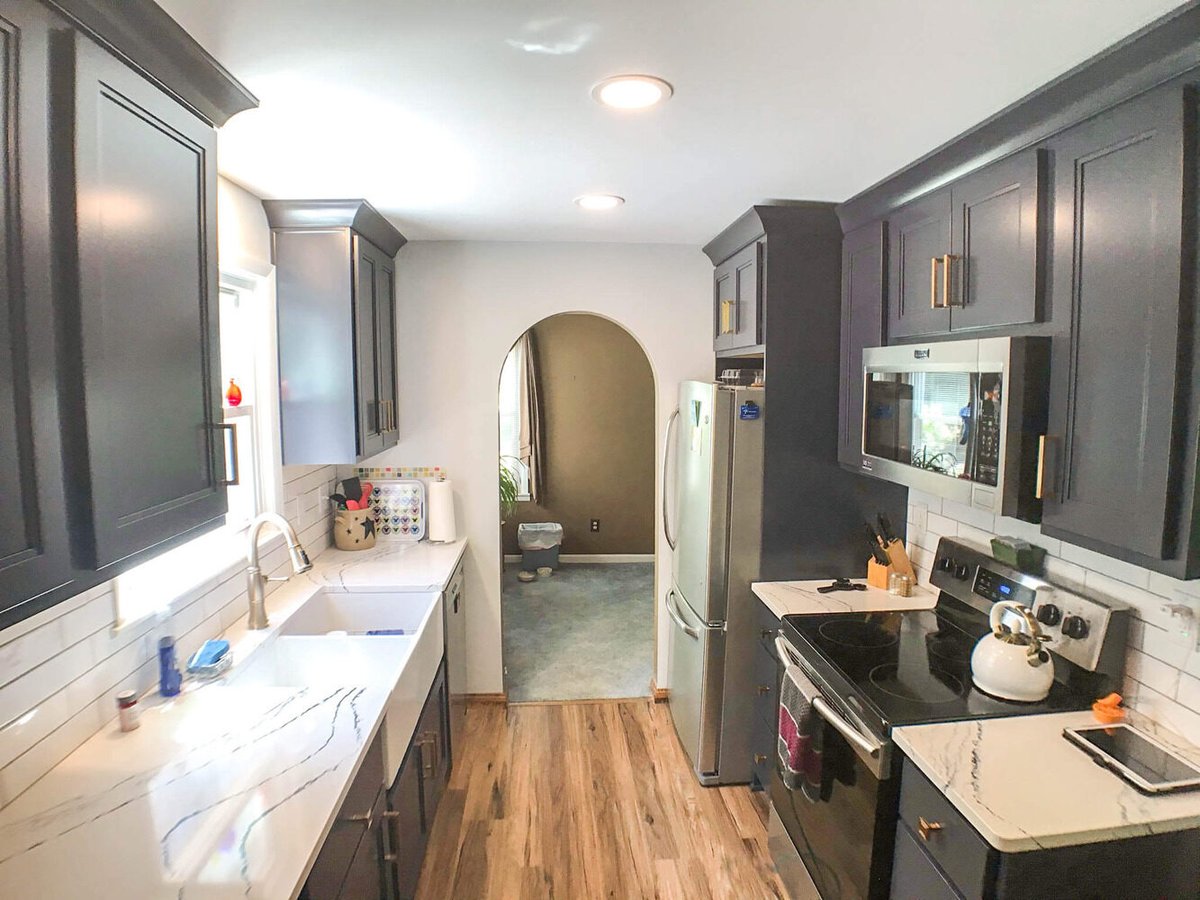 kitchen remodel featuring navy cabinets, stainless appliances, quartz countertops, and wood flooring by Odd Fellows Contracting in Williamston, MI