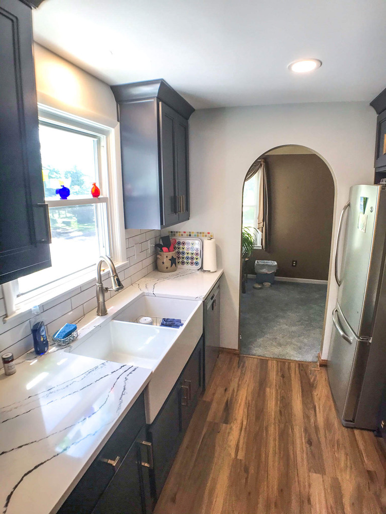 remodeled kitchen with quartz countertops, farmhouse sink, and navy shaker cabinets by Odd Fellows Contracting in Williamston, MI