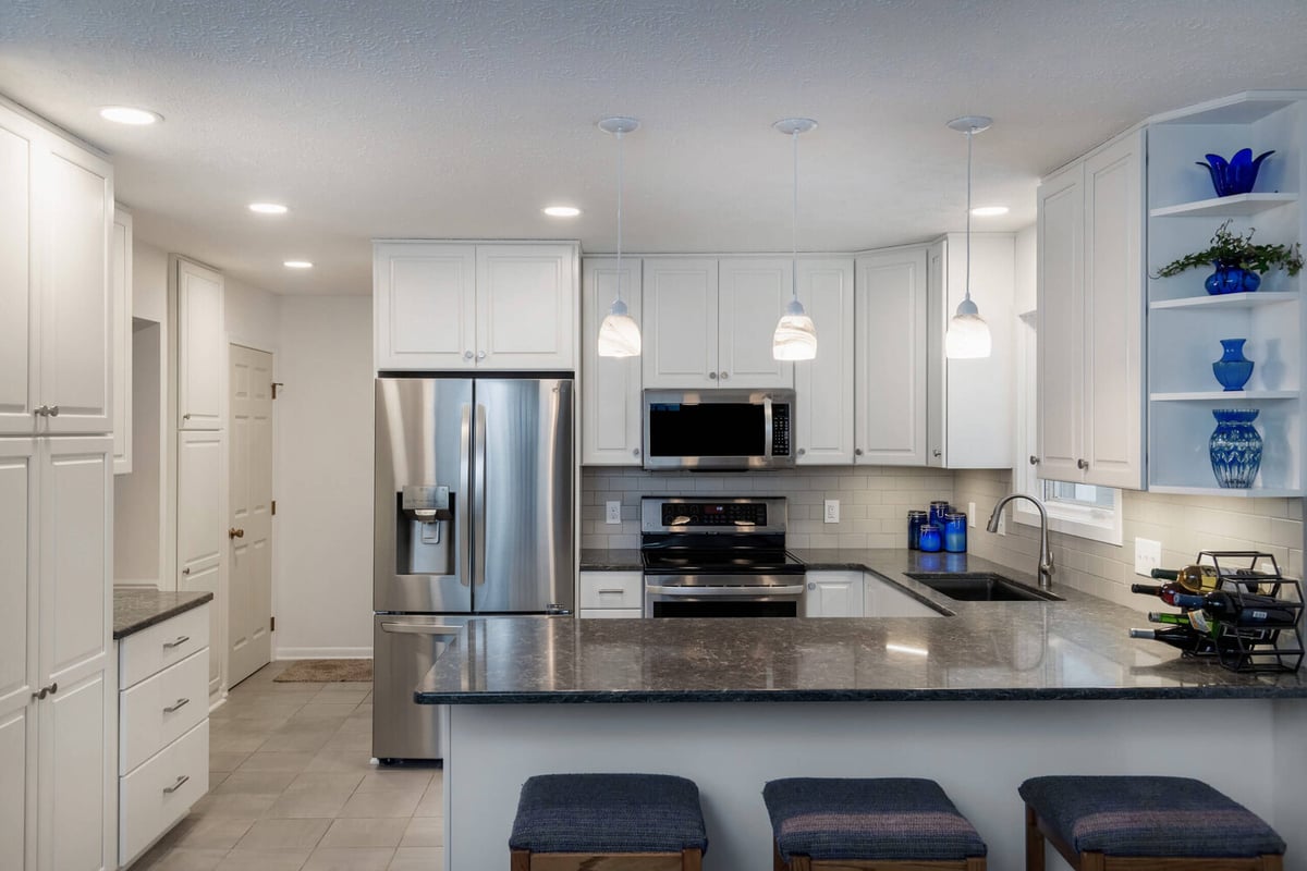 Full kitchen remodel with large island, white cabinets, and stainless appliances by Odd Fellows Contracting in Haslett, MI