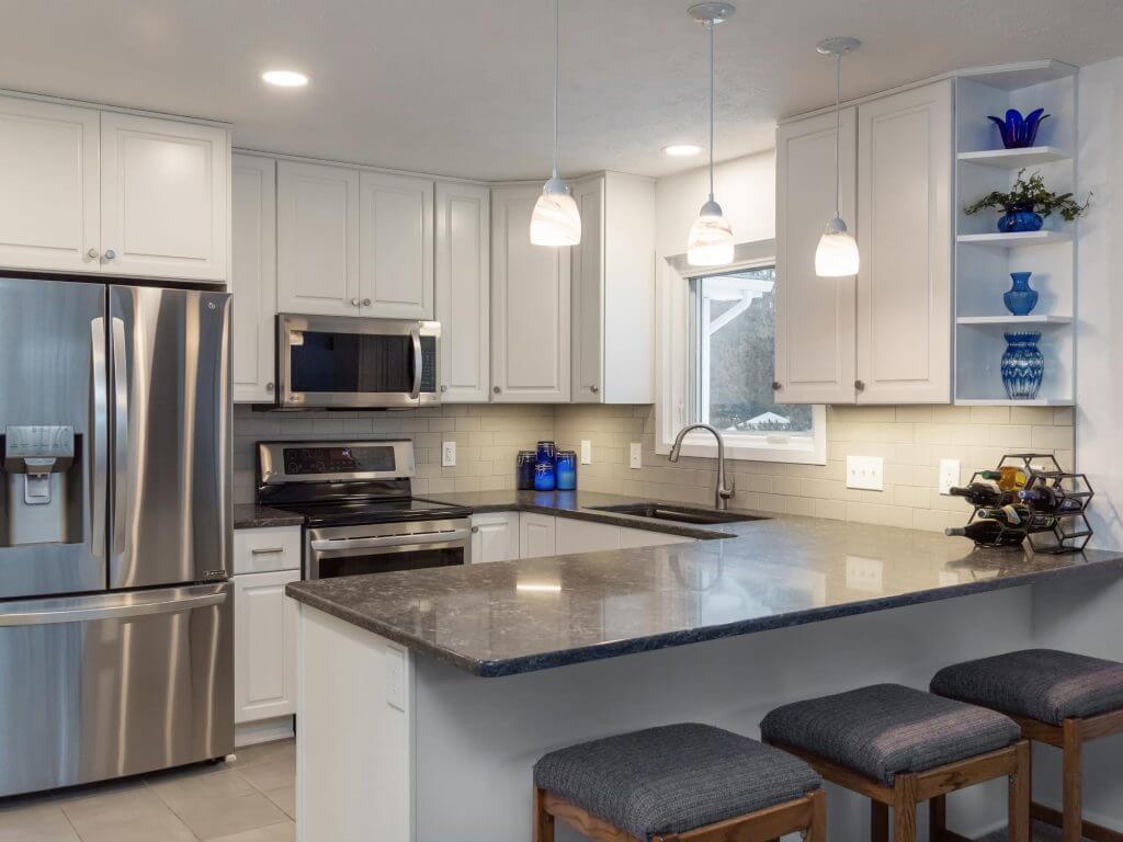 Modern white kitchen remodel with island and stainless appliances by Odd Fellows Contracting in Haslett, MI