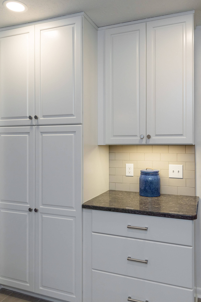 White pantry cabinets and drawer storage installed during kitchen remodel by Odd Fellows Contracting in Haslett, MI