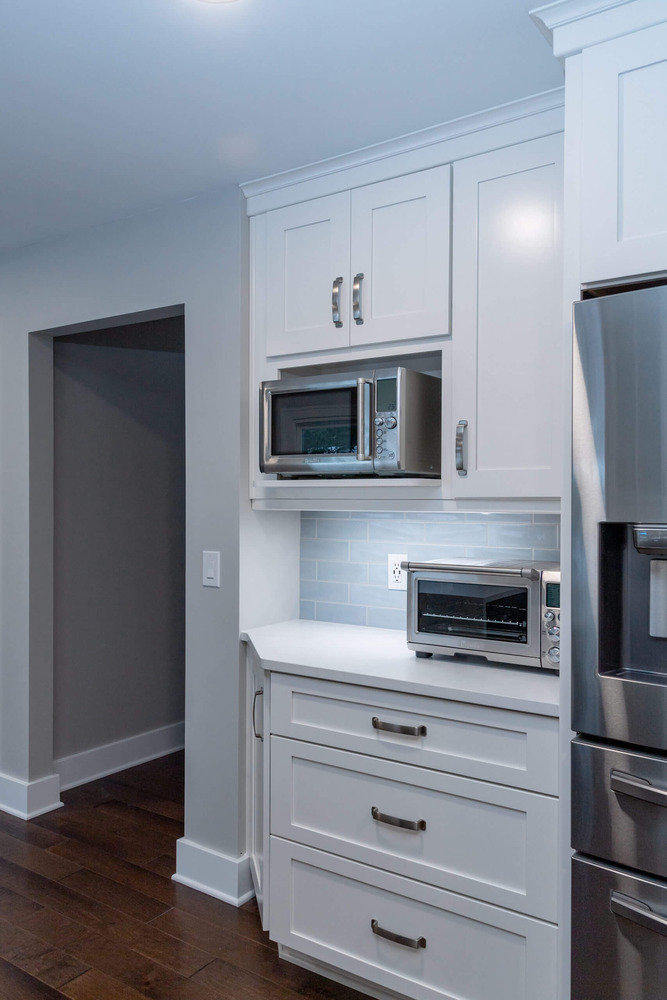 Custom kitchen cabinet station with microwave shelf and drawer storage by Odd Fellows Contracting in Okemos, MI