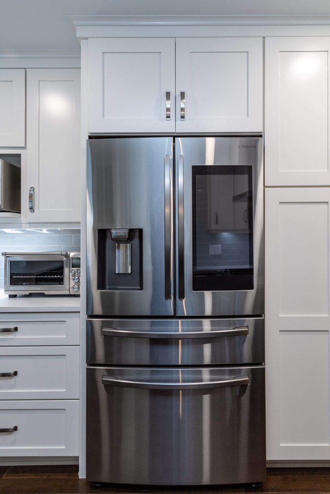 Kitchen remodel showing stainless smart refrigerator with custom cabinet surround by Odd Fellows Contracting in Okemos, MI