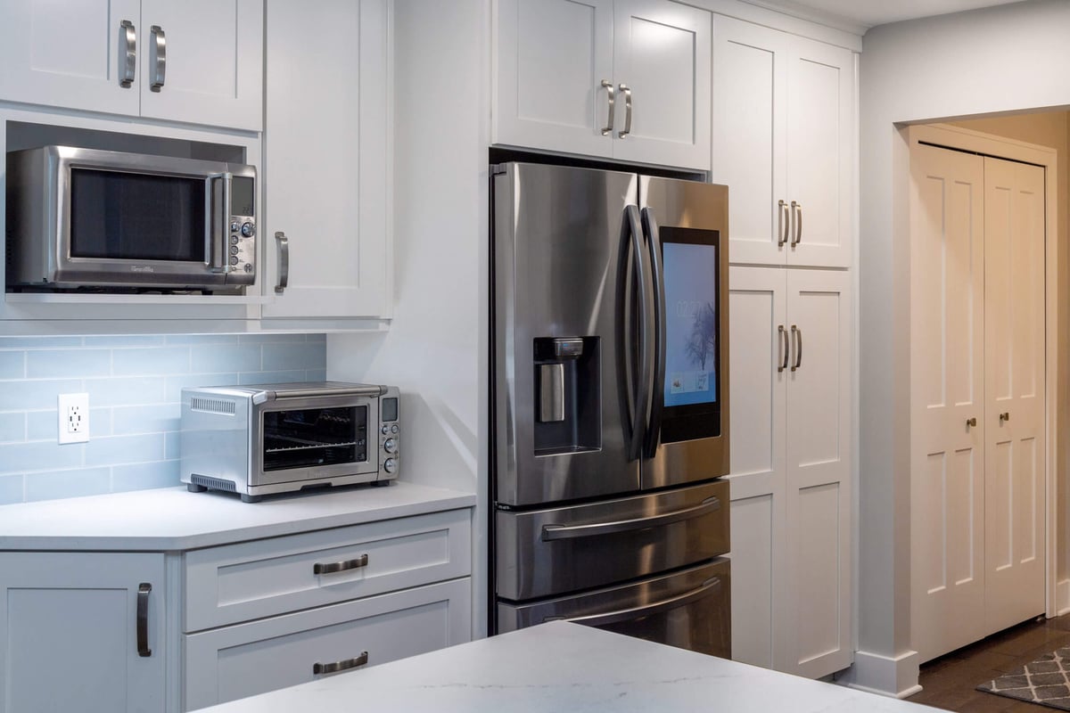 Kitchen remodel with stainless refrigerator and custom pantry cabinets by Odd Fellows Contracting in Okemos, MI