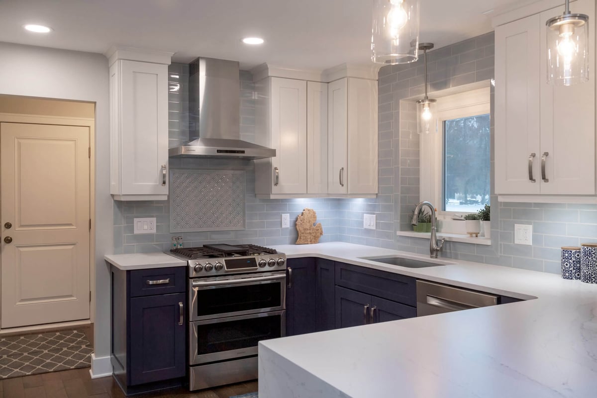 Updated kitchen appliance wall with white cabinetry and subway tile backsplash by Odd Fellows Contracting in Okemos, MI