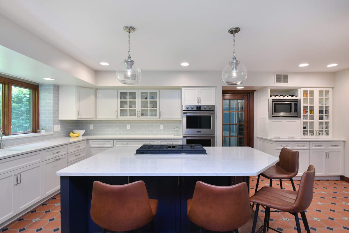 spacious kitchen renovation with white cabinets and island cooktop by Odd Fellows Contracting in Okemos, MI