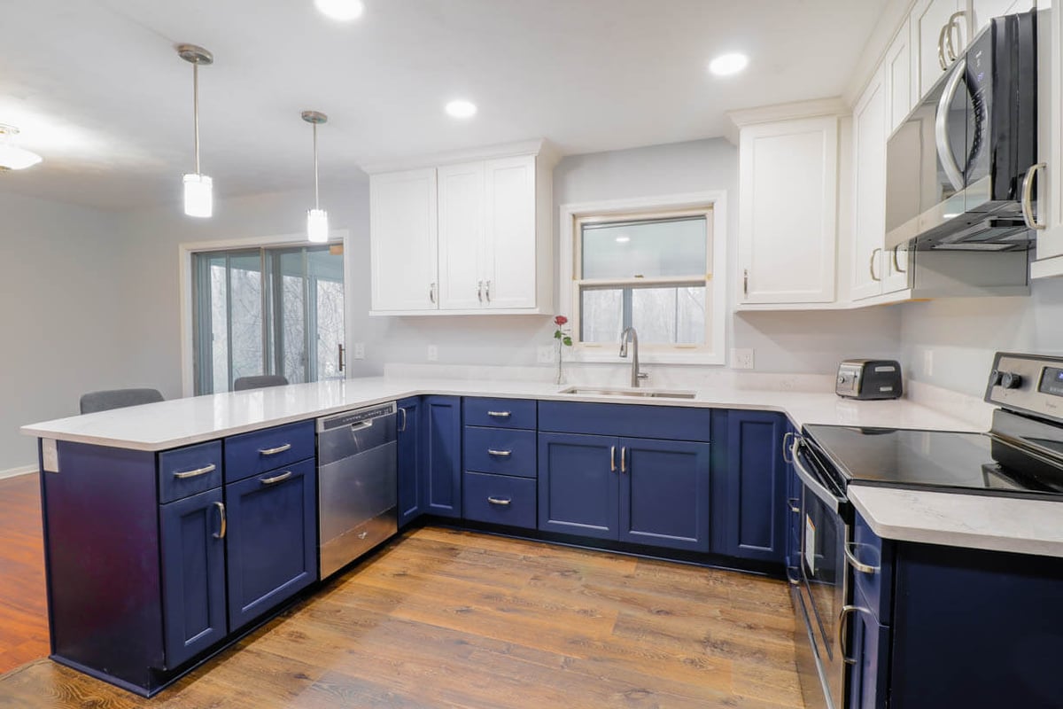 Renovated kitchen in West Lansing, MI by Odd Fellows Contracting with white upper cabinets and stainless steel appliances.