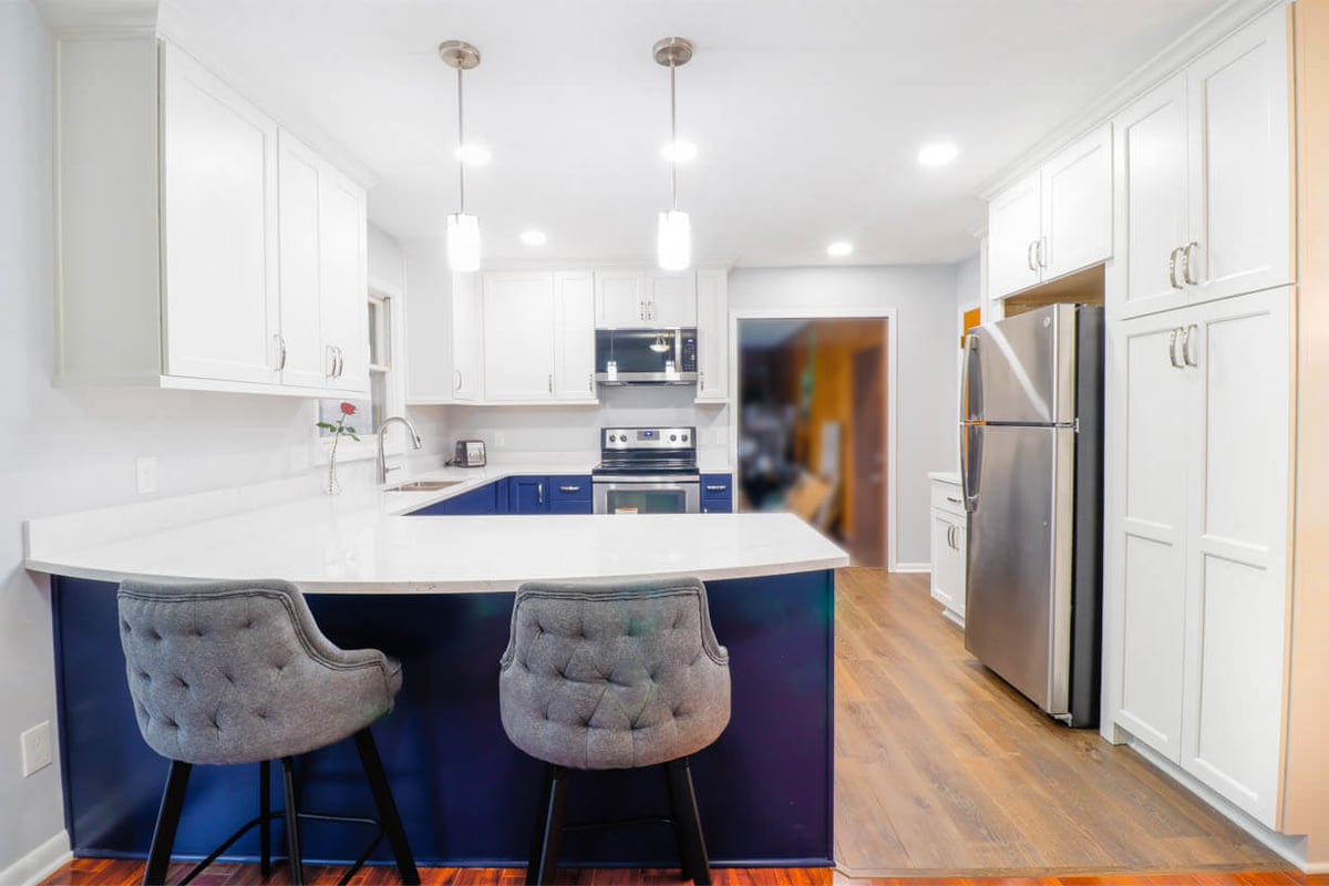 Updated kitchen island in West Lansing, MI by Odd Fellows Contracting with modern hardware and lighting.