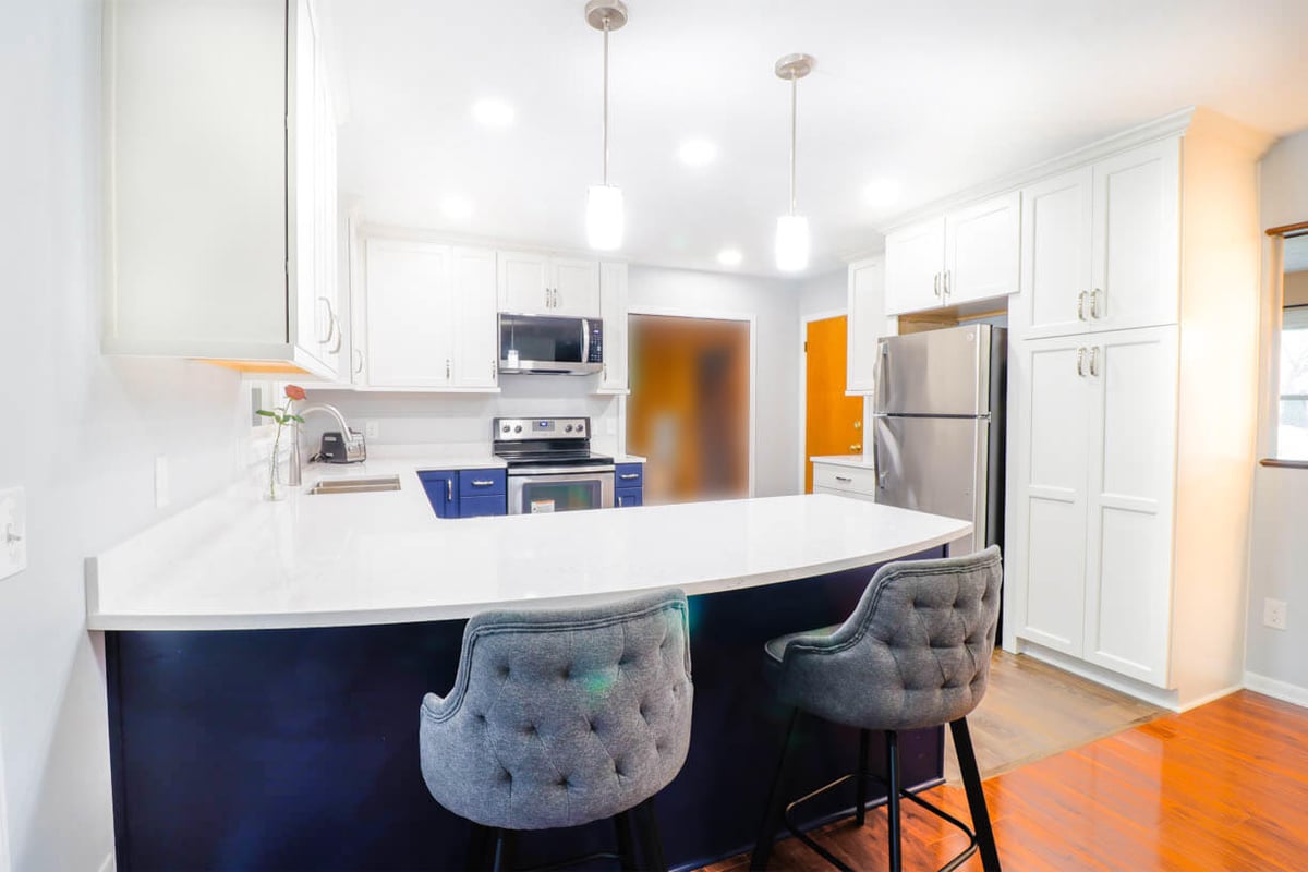 West Lansing, MI kitchen remodel by Odd Fellows Contracting highlighting blue cabinetry and bar seating.