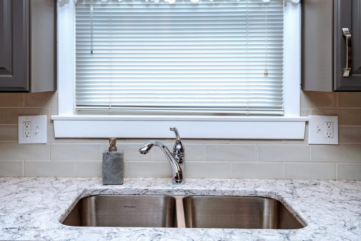 kitchen sink with quartz countertop and subway tile backsplash by Odd Fellows Contracting in Lansing, MI