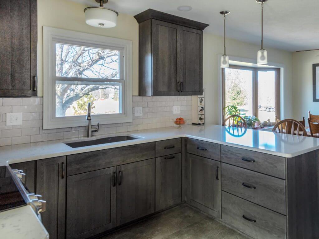 kitchen remodel with gray cabinets quartz island and pendant lighting by Odd Fellows Contracting in Onondaga, MI