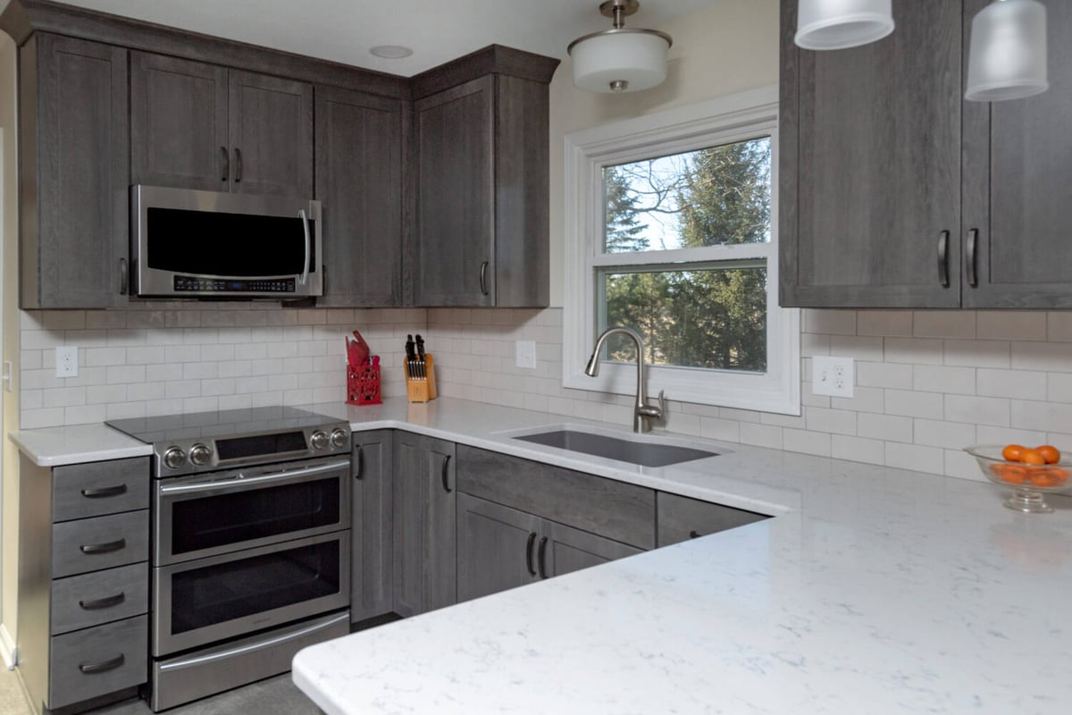 modern kitchen remodel with gray cabinetry and white quartz counters by Odd Fellows Contracting in Onondaga, MI