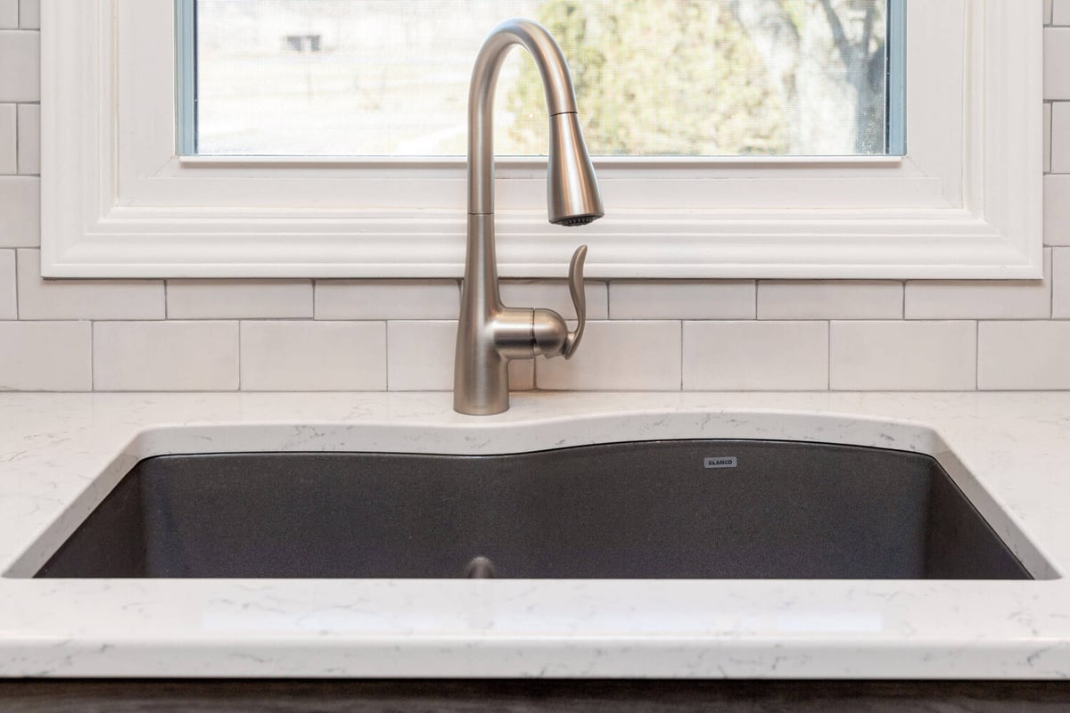 remodeled kitchen sink area with modern faucet and quartz counters by Odd Fellows Contracting in Onondaga, MI