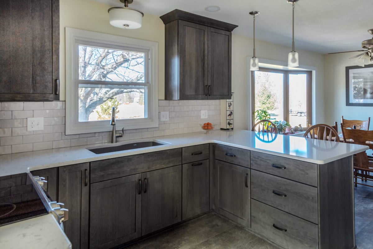 updated kitchen with window sink and quartz countertop peninsula by Odd Fellows Contracting in Onondaga, MI