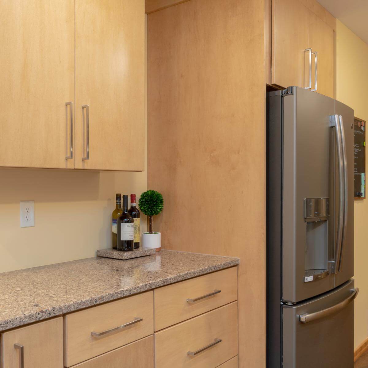 Custom kitchen cabinetry and stainless steel refrigerator in remodeled East Lansing Michigan kitchen by Odd Fellows Contracting