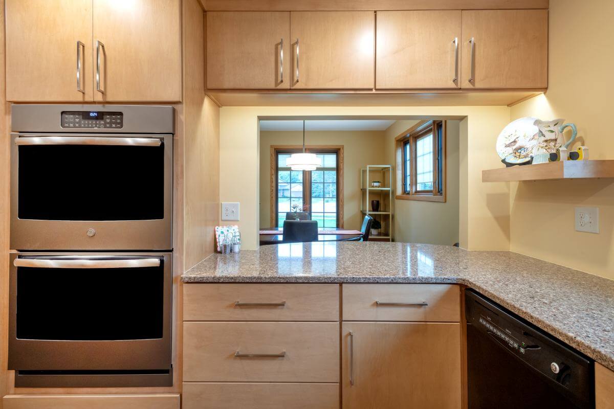 Kitchen pass-through opening to dining room with custom cabinets and countertop by Odd Fellows Contracting in East Lansing MI