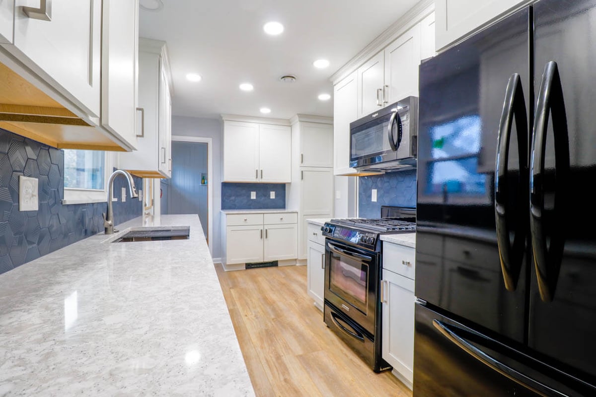 renovated kitchen in Cumberland Lansing, MI by Odd Fellows Contracting featuring quartz countertops and updated lighting
