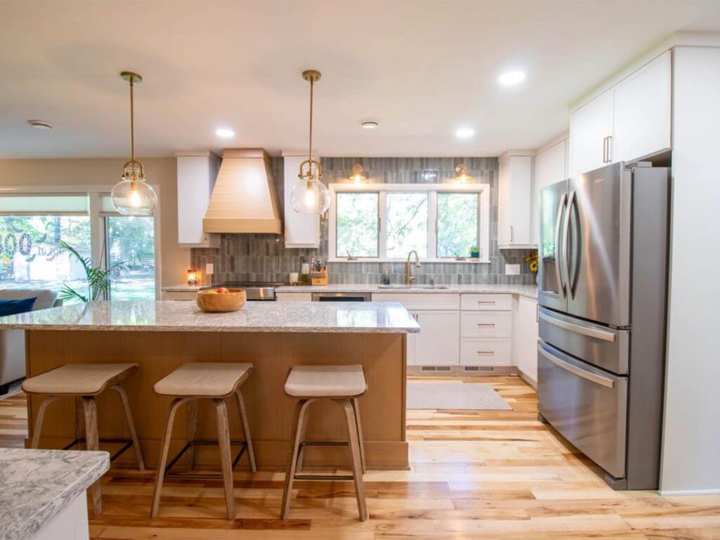 finished open concept kitchen remodel by Odd Fellows Contracting in Hiawatha Lakes, Okemos, MI featuring oversized island and stainless steel appliances