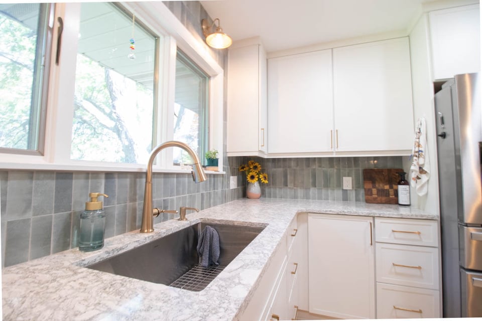 kitchen sink and backsplash detail from remodel by Odd Fellows Contracting in Hiawatha Lakes, Okemos, MI with brass faucet and white cabinetry
