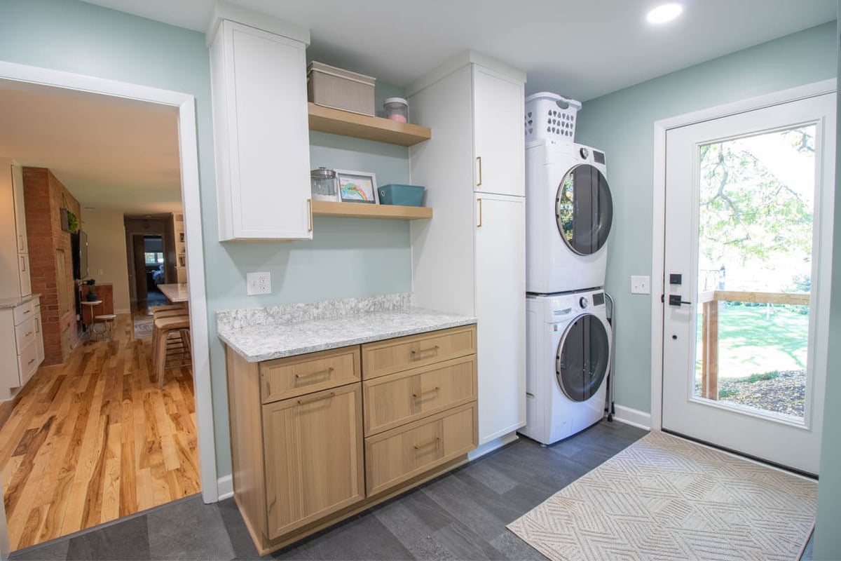 laundry and mudroom remodel by Odd Fellows Contracting in Hiawatha Lakes, Okemos, MI featuring stacked washer and dryer, custom cabinetry, and quartz countertop
