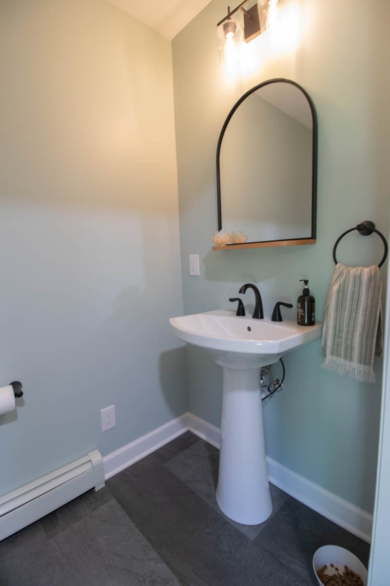 updated powder room remodel by Odd Fellows Contracting in Hiawatha Lakes, Okemos, MI with pedestal sink and arched mirror
