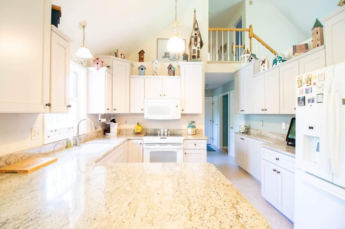 remodeled kitchen by Odd Fellows Contracting in Williamston, MI with large granite island and white appliances
