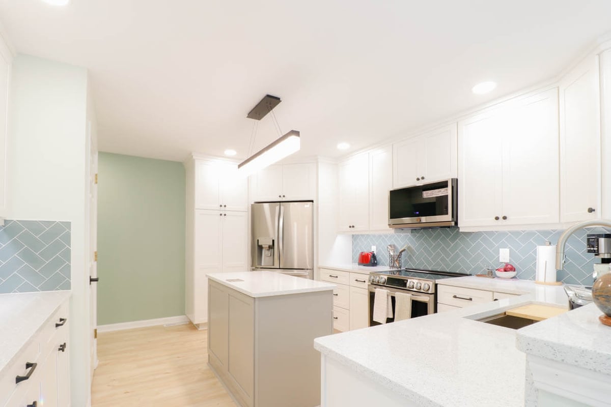 after kitchen remodel by Odd Fellows Contracting in Emerald Lake, MI with white shaker cabinets and quartz island